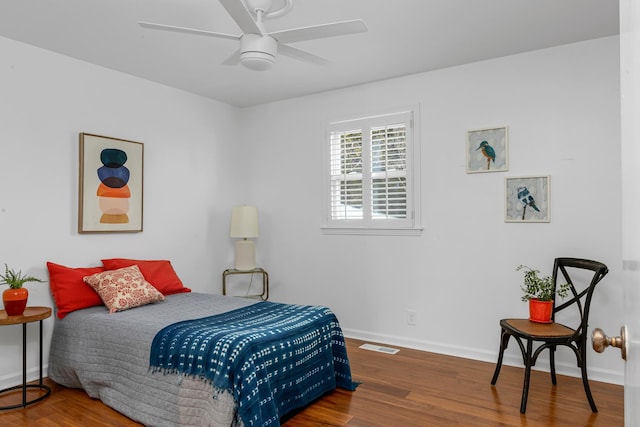 bedroom featuring a ceiling fan, visible vents, baseboards, and wood finished floors