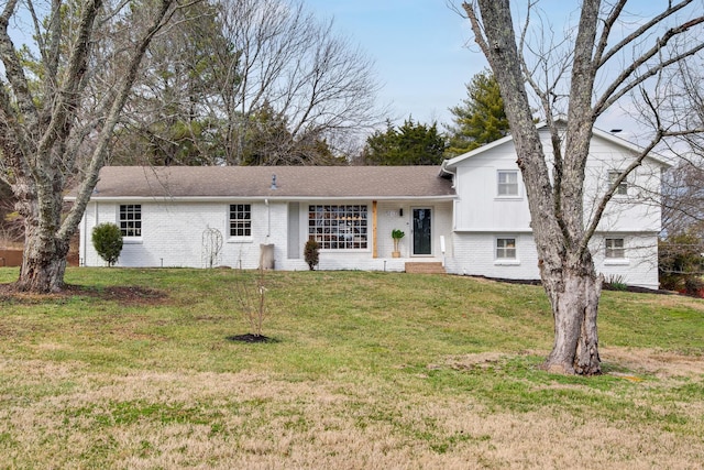 tri-level home with a front yard and brick siding