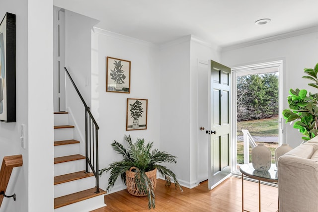 foyer with crown molding, light wood finished floors, and stairs