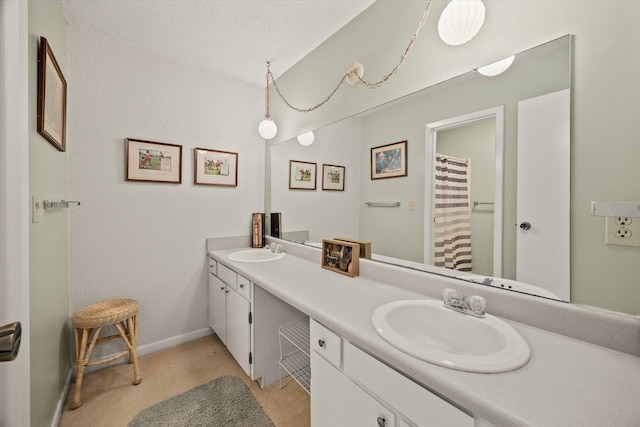 full bathroom featuring double vanity, baseboards, and a sink