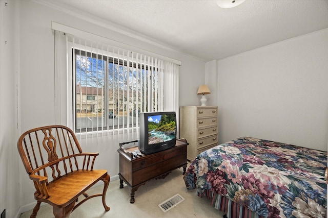 bedroom featuring light carpet, visible vents, and a textured ceiling