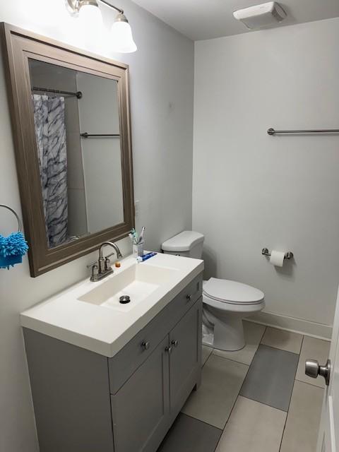 bathroom featuring baseboards, visible vents, vanity, and toilet