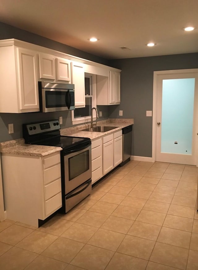 kitchen with light tile patterned floors, white cabinets, stainless steel appliances, a sink, and recessed lighting