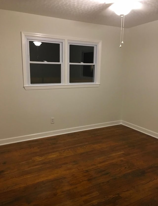 empty room featuring dark wood-style floors and baseboards