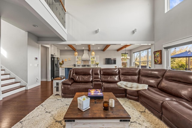 living area with a towering ceiling, plenty of natural light, dark wood-style flooring, and beamed ceiling