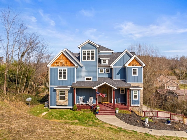 view of front facade with a front lawn, a porch, board and batten siding, and roof with shingles