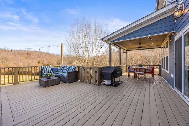 wooden deck featuring outdoor dining area, outdoor lounge area, a grill, and a ceiling fan