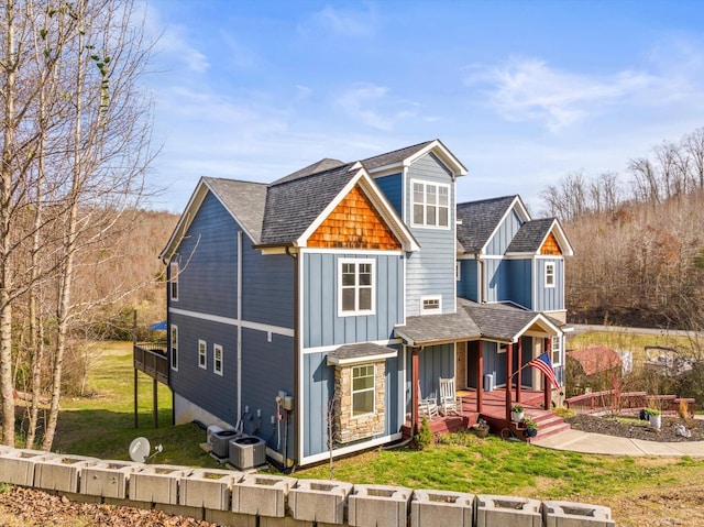 view of front of house with a front lawn, board and batten siding, and roof with shingles