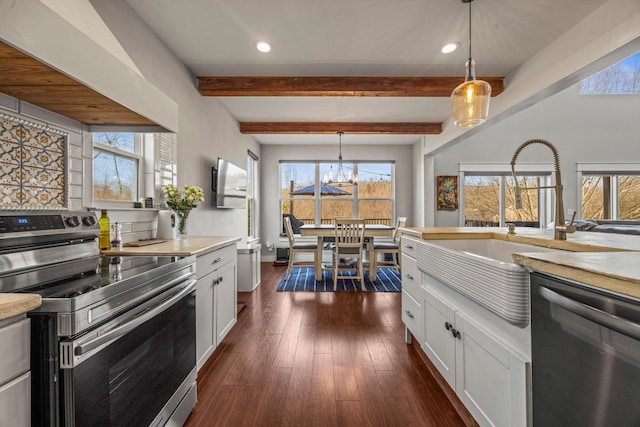 kitchen with stainless steel appliances, dark wood-style flooring, white cabinets, light countertops, and decorative light fixtures