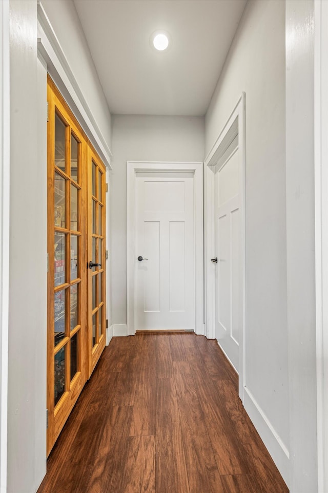 hall with dark wood-type flooring and baseboards