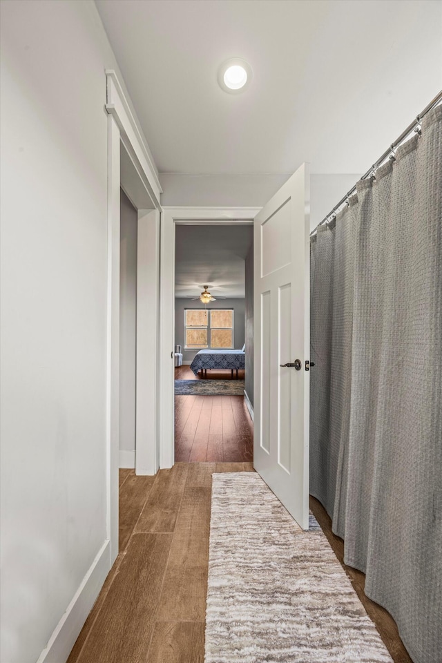 hallway with baseboards and wood finished floors