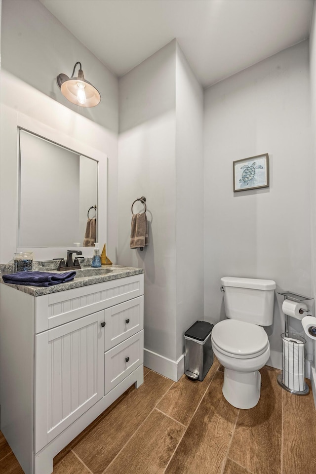 bathroom featuring toilet, wood finished floors, vanity, and baseboards