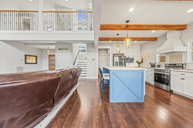 kitchen with open floor plan, hanging light fixtures, appliances with stainless steel finishes, light countertops, and custom range hood