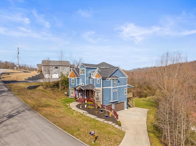 view of front of property with a garage, a porch, concrete driveway, and a front yard