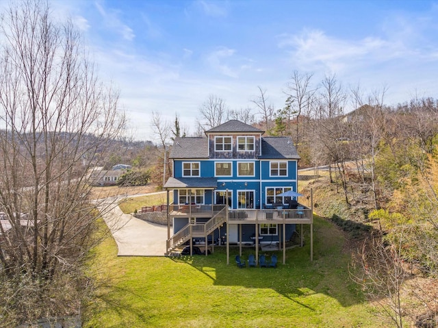 rear view of house featuring stairway, a deck, and a lawn