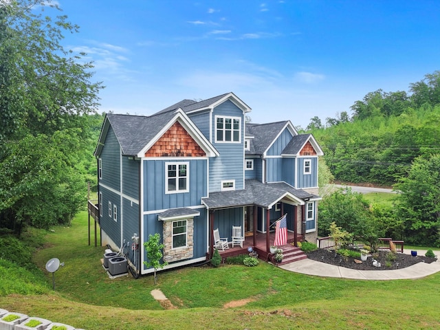 craftsman house with a porch, central AC unit, board and batten siding, and a front yard