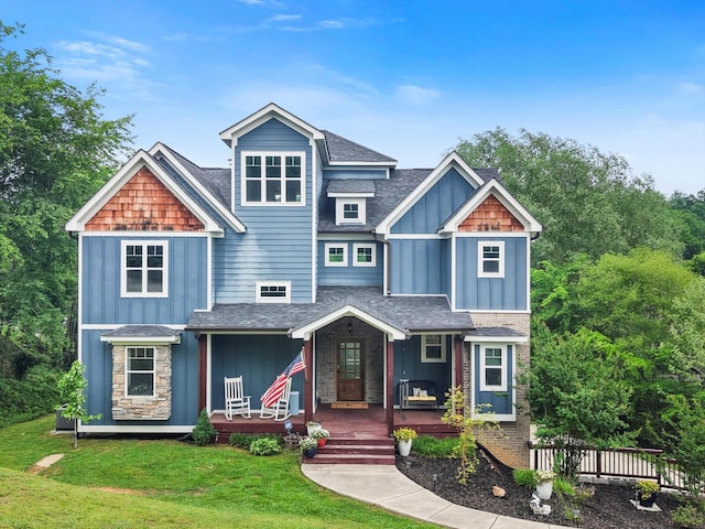 craftsman-style house featuring board and batten siding, a shingled roof, a porch, and a front lawn