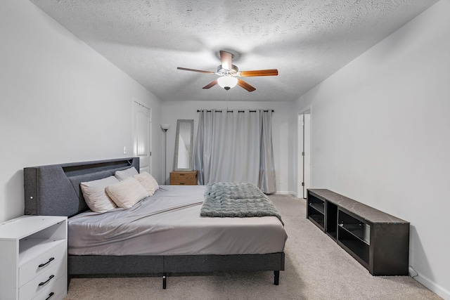 bedroom featuring light carpet, ceiling fan, a textured ceiling, and baseboards