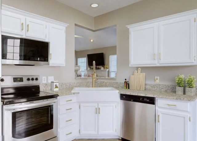 kitchen featuring light stone countertops, appliances with stainless steel finishes, white cabinets, and a sink