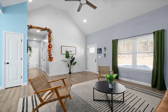 living room featuring light wood finished floors, attic access, ceiling fan, high vaulted ceiling, and baseboards