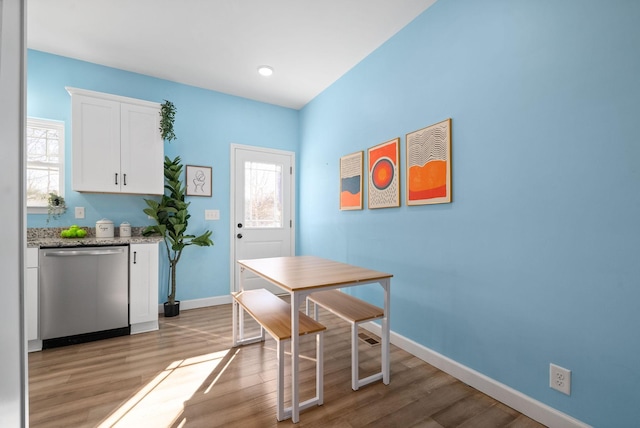 dining area featuring a healthy amount of sunlight, light wood finished floors, and baseboards