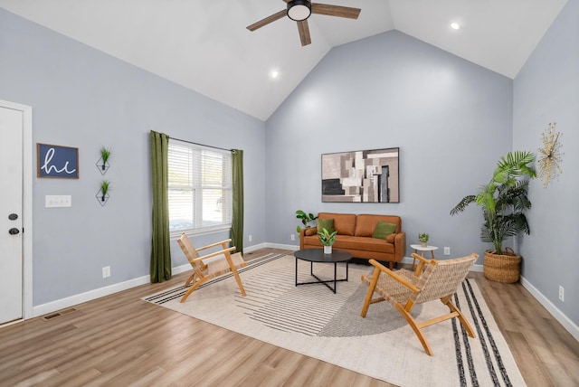 living area with high vaulted ceiling, baseboards, light wood finished floors, and a ceiling fan