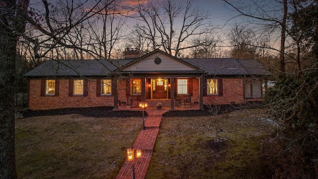 view of front of property with crawl space, a porch, a lawn, and brick siding