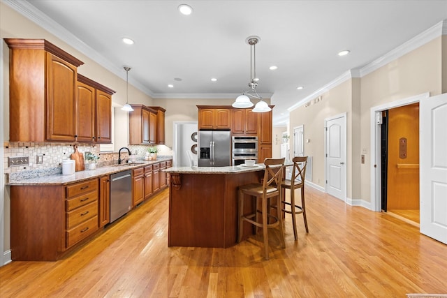 505 Wilcox St, Clarksville, TN 37040 - kitchen with light stone counters, a center island, decorative light fixtures, stainless steel appliances, and brown cabinetry