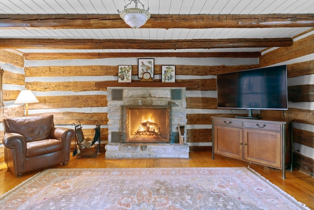 living room featuring light wood-style floors, beam ceiling, wooden ceiling, and a stone fireplace