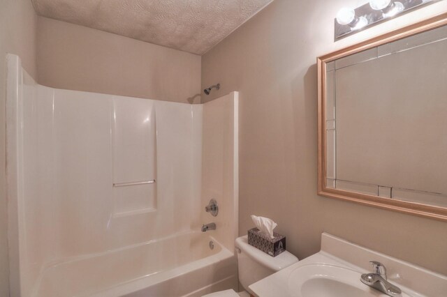 bathroom with a textured ceiling, shower / bathtub combination, vanity, and toilet