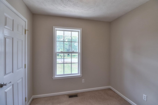 spare room featuring a healthy amount of sunlight, baseboards, visible vents, and light colored carpet