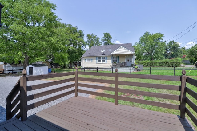 wooden terrace featuring a storage shed, a yard, an outbuilding, and a fenced backyard