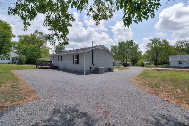 view of side of property with driveway, a yard, and central air condition unit