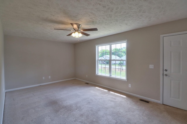 spare room with a ceiling fan, light colored carpet, visible vents, and baseboards