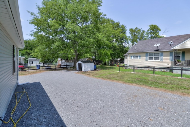 view of yard featuring a shed, an outdoor structure, and fence