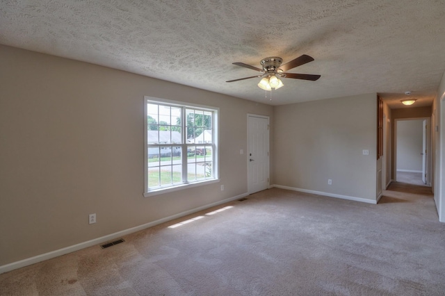 unfurnished room with visible vents, a ceiling fan, light carpet, a textured ceiling, and baseboards