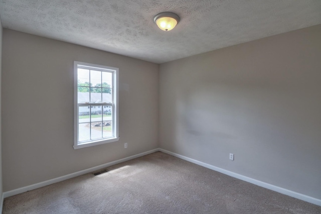 unfurnished room with baseboards, visible vents, a textured ceiling, and carpet flooring