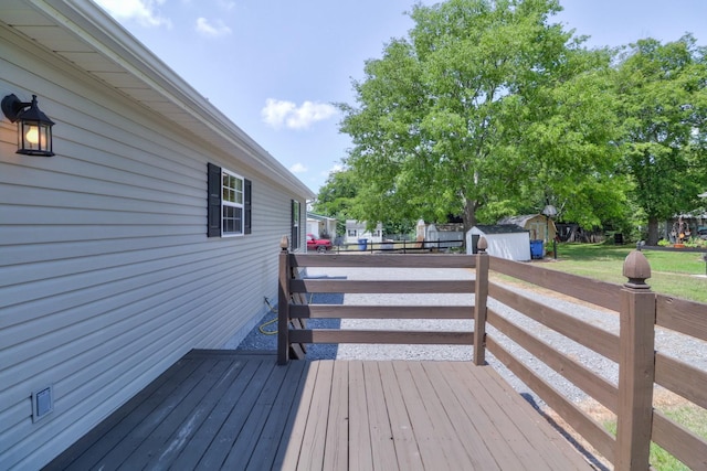 wooden terrace featuring a storage unit and an outdoor structure