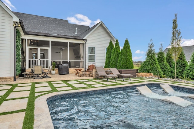 rear view of property with ceiling fan, a shingled roof, a sunroom, an outdoor pool, and a patio area