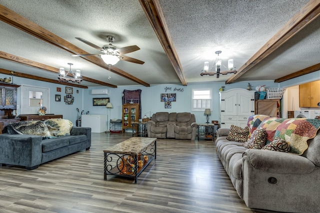 living area with a textured ceiling, a wall unit AC, ceiling fan with notable chandelier, wood finished floors, and beam ceiling