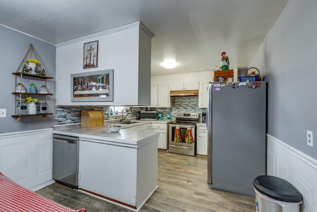 kitchen with a peninsula, white cabinetry, appliances with stainless steel finishes, and light countertops