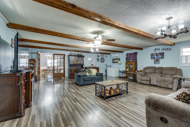 living area with a wall mounted AC, a textured ceiling, wood finished floors, beamed ceiling, and ceiling fan with notable chandelier