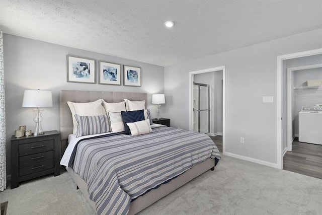 bedroom featuring a textured ceiling, washer / clothes dryer, light colored carpet, and baseboards