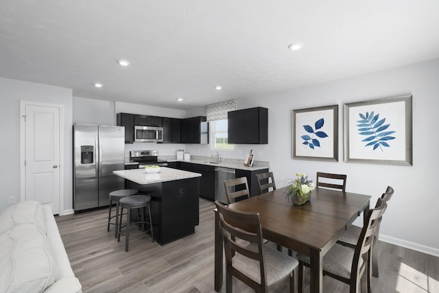 dining area with light wood-style flooring, baseboards, and recessed lighting