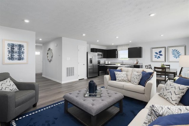 living area featuring a textured ceiling, visible vents, dark wood-style flooring, and recessed lighting