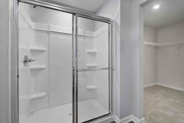 bathroom with a stall shower, a walk in closet, and baseboards