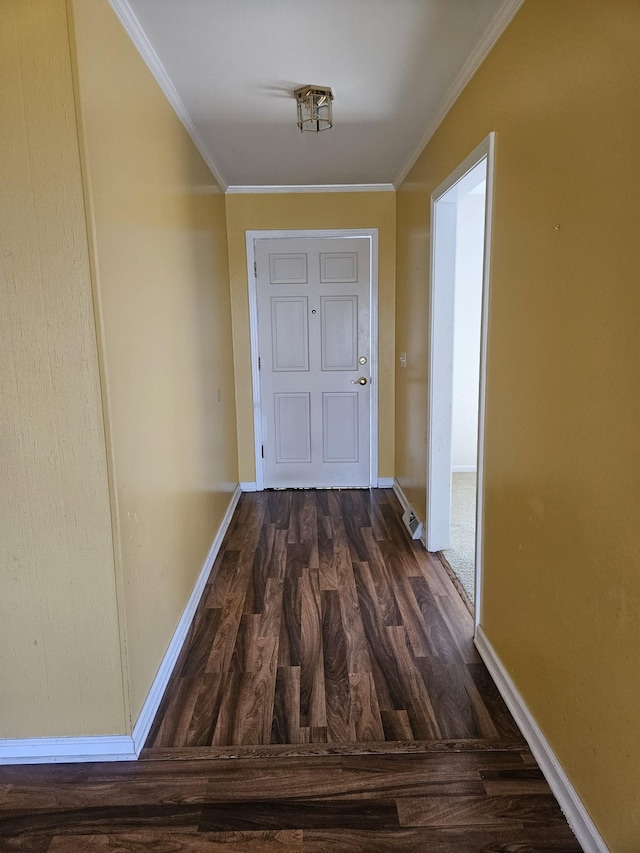 hallway featuring ornamental molding, dark wood-type flooring, and baseboards