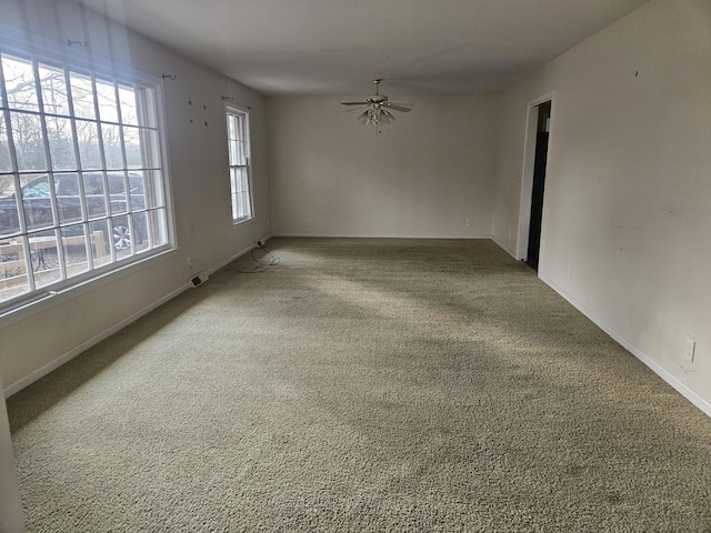 carpeted empty room featuring baseboards and a ceiling fan