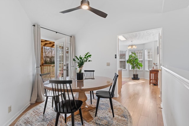 dining area featuring ceiling fan with notable chandelier, light wood finished floors, and baseboards