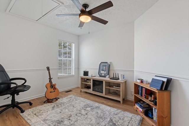 home office featuring light wood-type flooring, attic access, visible vents, and a textured ceiling